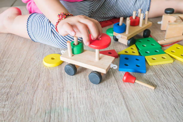 Body part of baby girl playing the wooden block toys. On wooden floor. Body part of baby girl playing the wooden block toys. On wooden floor. 1-2 years old of child. Learning and development of kid concept. ASIAN CHILD PICKING TOYS stock pictures, royalty-free photos & images