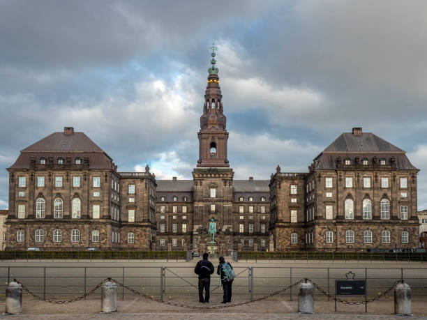 Magnificent view of the Chistiansborg Palace Copenhagen, Denmark - Oct 19, 2018: Magnificent view of the Chistiansborg Palace. Classic European architectural building design. At Slotsholmen. Two visitors at front admiring the grandeur. sentinel spire stock pictures, royalty-free photos & images