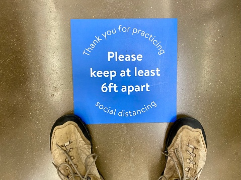Social distancing sign on store floor and shoes