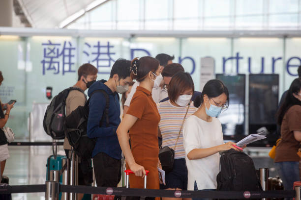 passagiere mit masken stehen am check-in-schalter des hong kong international airport schlange. - airport check in counter fotos stock-fotos und bilder