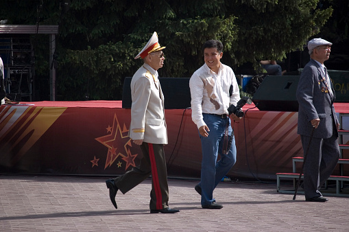 American soldier in uniform and civil man in suit shaking hands with certain USA state flag on background - California