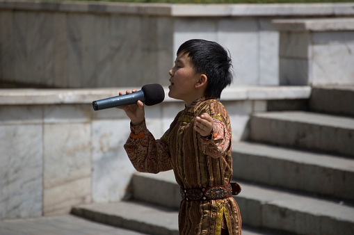 A kazakh boy singing during a festival event in Almaty City. The image was captured during springtime.