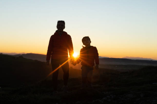 istock Mother and son silhouetted at sunset when walking 1429602771