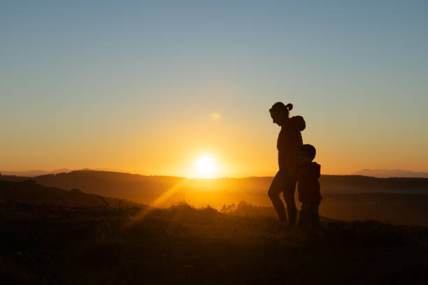 istock Mother and son silhouetted at sunset when walking 1429602847