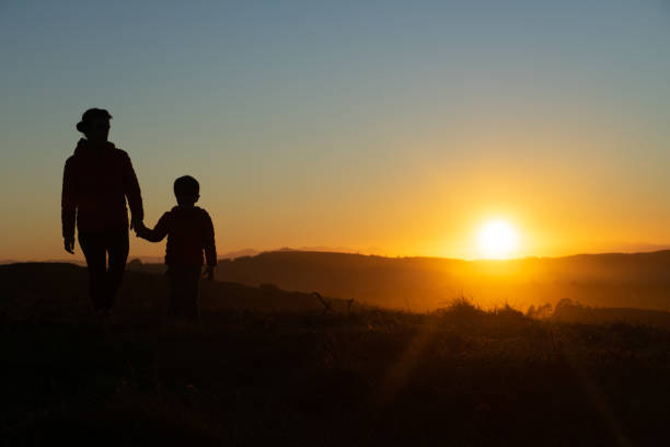 istock Mother and son silhouetted at sunset when walking 1429602851