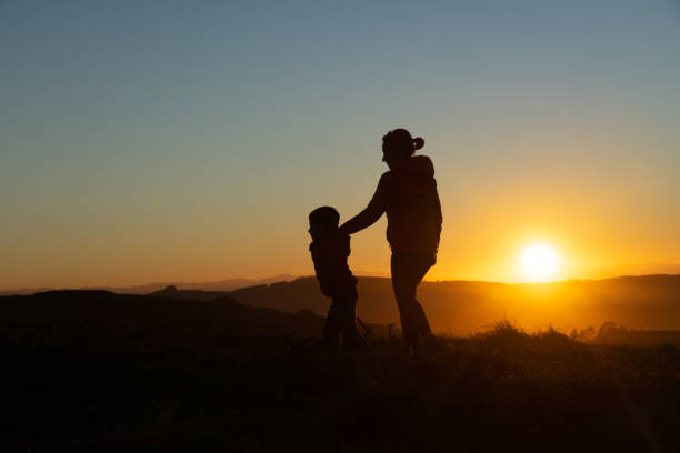 istock Mother and son silhouetted at sunset when walking 1429602897