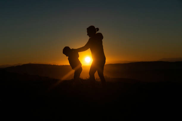 istock Mother and son silhouetted at sunset when walking 1429602903