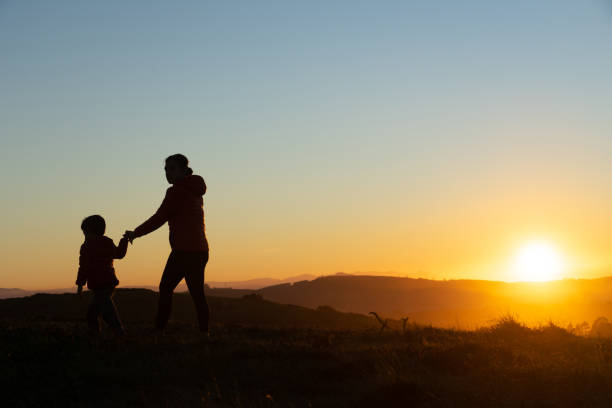 istock Mother and son silhouetted at sunset when walking 1429602964