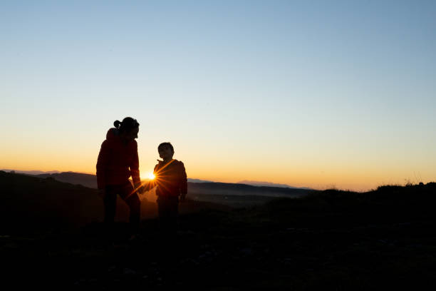 istock Mother and son silhouetted at sunset when walking 1429603024
