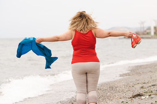 Excited overweight woman needing her arms on the beach