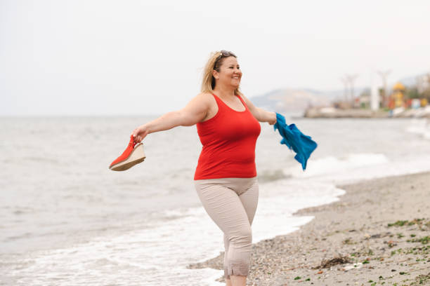 Cheerful crazy overweight woman dancing by the sea