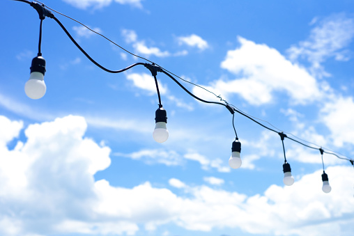a lot of light bulbs hanging against a blue sky with clouds