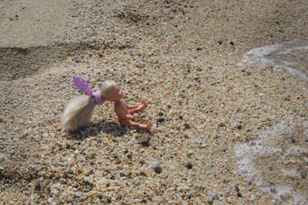 Little plastic doll on the sand beach