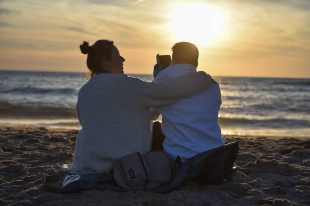 istock a couple sits romantically on the beach at sunset 1429616298