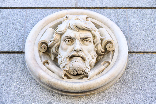 Madrid, Spain - September 30, 2022: White marble carving decorating the facade of the Bank of Spain. The detail is a sculpted face of a man with a beard.