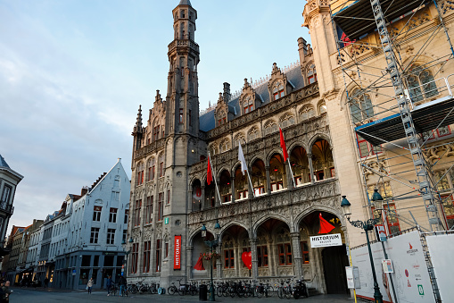 Bruges, Belgium - September 14, 2022: Historium museum building located at the town square is visible here on summer early evening. There is scaffolding on the building next door.