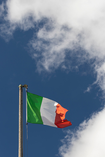 Italian flag blowing in the wind in the blue sky