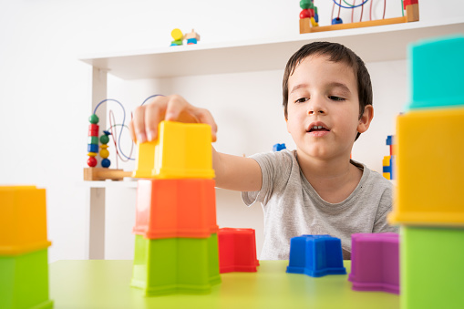 Shot of an adorable little boy playing with plastic blocks at home