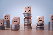 Coin stacking on smiley face and sad face for good financial planing can make happiness in life, Money saving and investment concept.