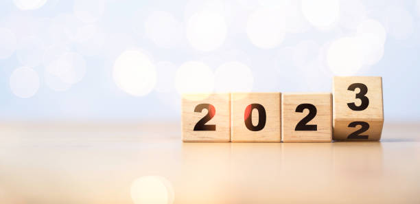 invertendo o cubo de bloco de madeira para mudar de 2022 para 2023 com bokeh para feliz natal e feliz conceito de preparação para o ano novo. - year block cube new years eve - fotografias e filmes do acervo