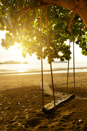 Wooden swing on the beach when sunrise at the morning.