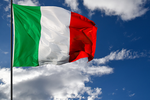 Italian flag waving on blue sky with white clouds