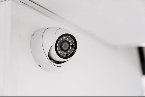 CCTV camera with broken glass on a white wall under the ceiling. security systems for home and office.