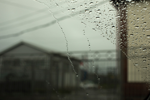 Raindrops on glass. Rainy weather outside window. Gray sky.