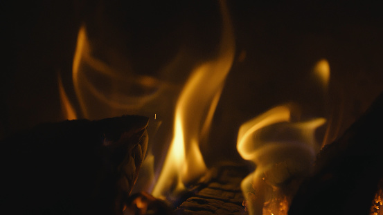 Fireplace, flames over wooden logs. Cozy fire. Close up, Macro. Burning firewood. Depth of field