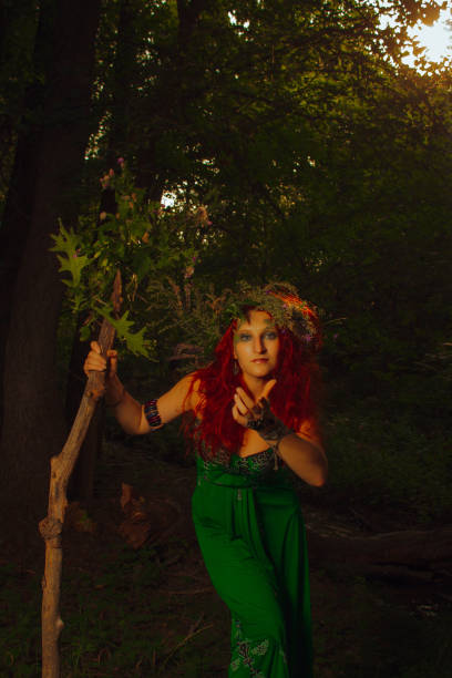 Redhead beautiful lady in green dress posing in the forest