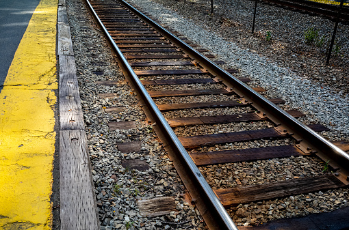 Different views of railroad tracks taken at the Wellesley Farms Commuter rail station in Wellesley, MA just outside of Boston, MA.  In addition to the rails, the photos show the bold yellow caution line and the \