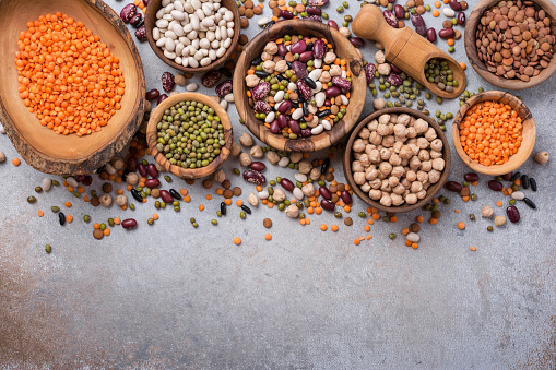 Top view of an assortment of legume family rich on vegan protein such as kidney beans, chickpeas, pea pods, lentils and green soy beans with copy space on the counter top