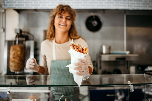 Woman works in a fast food shop, prepares the best gyros