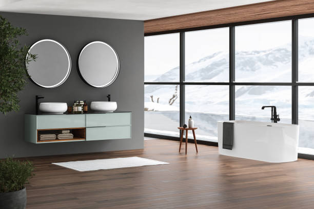 istock Modern bathroom interior with dark brown parquet floor, white oval bathtub and two sinks, side view. Minimalist bathroom with modern furniture , pool and snowy mountain view from window. 3D rendering 1429679536