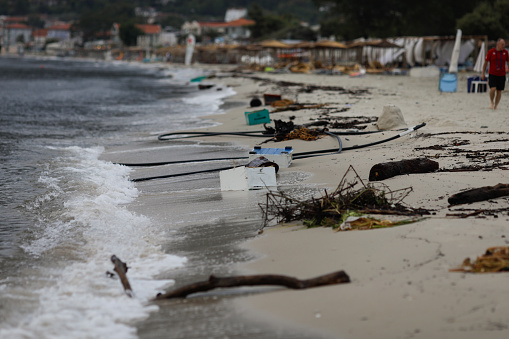 Wood, plastic and even wooden bee hives washed ashore on the Golden Beach in Thassos after a powerful storm on a cloudy summer morning.