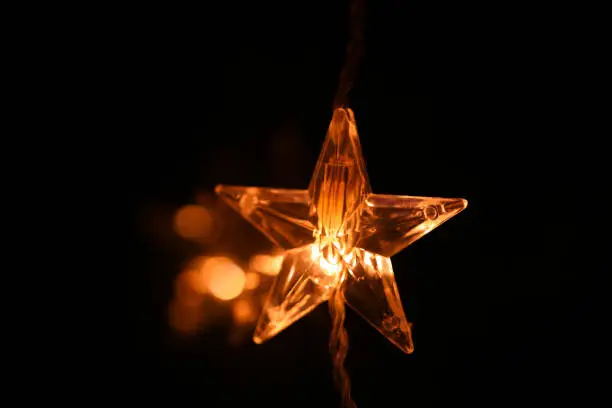 Christmas.Star burning on a black background.Festive glowing garlands on a dark background.Christmas and New Year festive background.