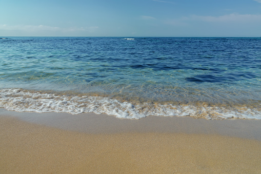 sunny morning scenery at the sea. calm waves washing the sandy beach. transparent water and bright blue sky