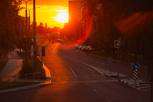 Road is illuminated by setting sun. City street. Evening light. Lens flare. Road markings. Sunset