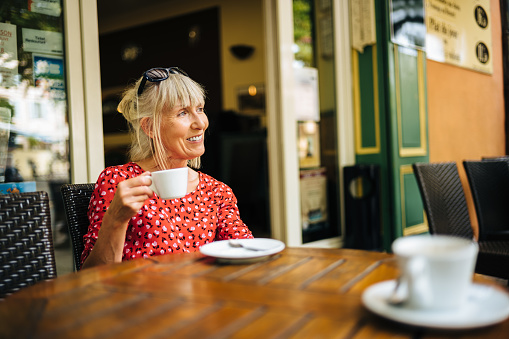 Mature woman relaxing with a cup of coffee in the village of Moustiers Sainte Marie in the Provence region of France.
