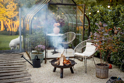 Beautiful and cozy garden with a picnic fire at lounge area and vintage greenhouse behind. Atmospheric and very beautiful courtyard of a country house