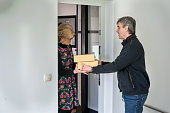 A man is delivering packed food to an address to an older female customer.