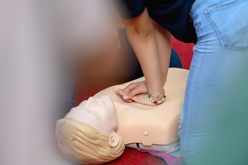 Close-up of instructor demonstrating chest compressions to volunteers