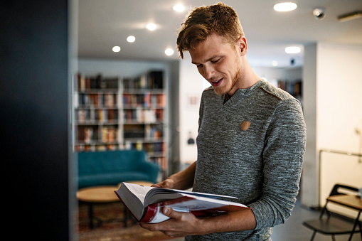 Student in library taking book from bookshelf