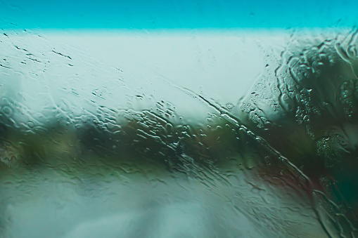 Raindrops on glass. Drops on window. Bad weather. Rainy season. Car. Road