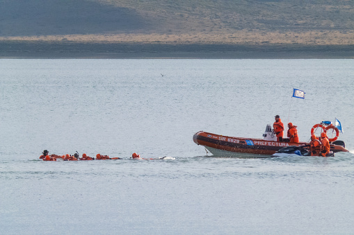 Rio Gallegos, Argentine - June 28, 2022 : Argentine naval prefecture training or practicing rescue with motorized inflatable boat and jet ski with several people in lifeguards