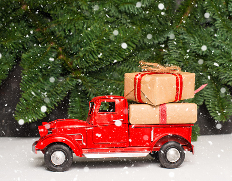 Vintage Christmas red car or truck carrying gift boxes.
