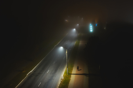 Night foggy street drone photography. Road with lanterns. Silhouette. Foggy weather. Bad visibility. Fog. Atmospheric mystical landscape.