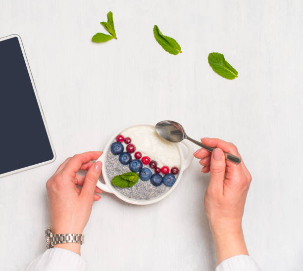 istock Healthy breakfast or morning snack with chia seeds pudding and berries on white background, woman eating healthy food. 1429711098