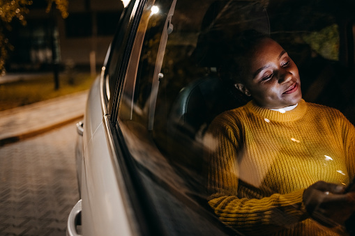 Woman driving in car at night and looking at digital tablet