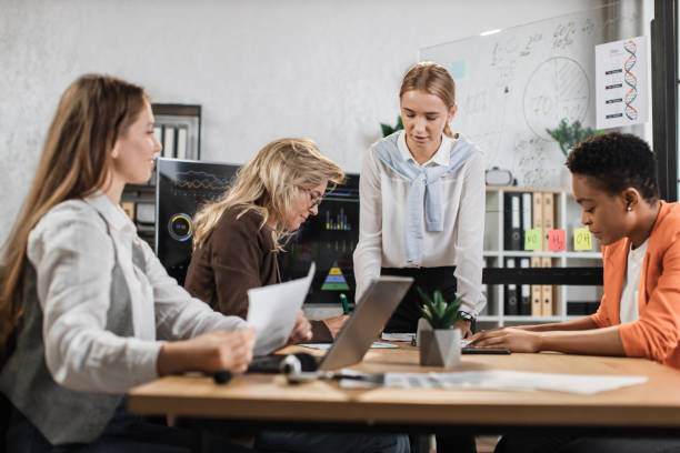 istock Group of competent female traders sitting together at office desk with various graphs and charts 1429726833